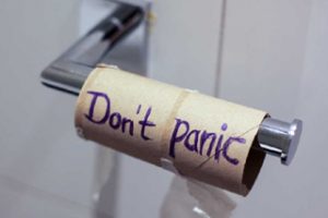 Leere Klopapierrolle auf Metallhalter mit Aufschrift "Don't panic"